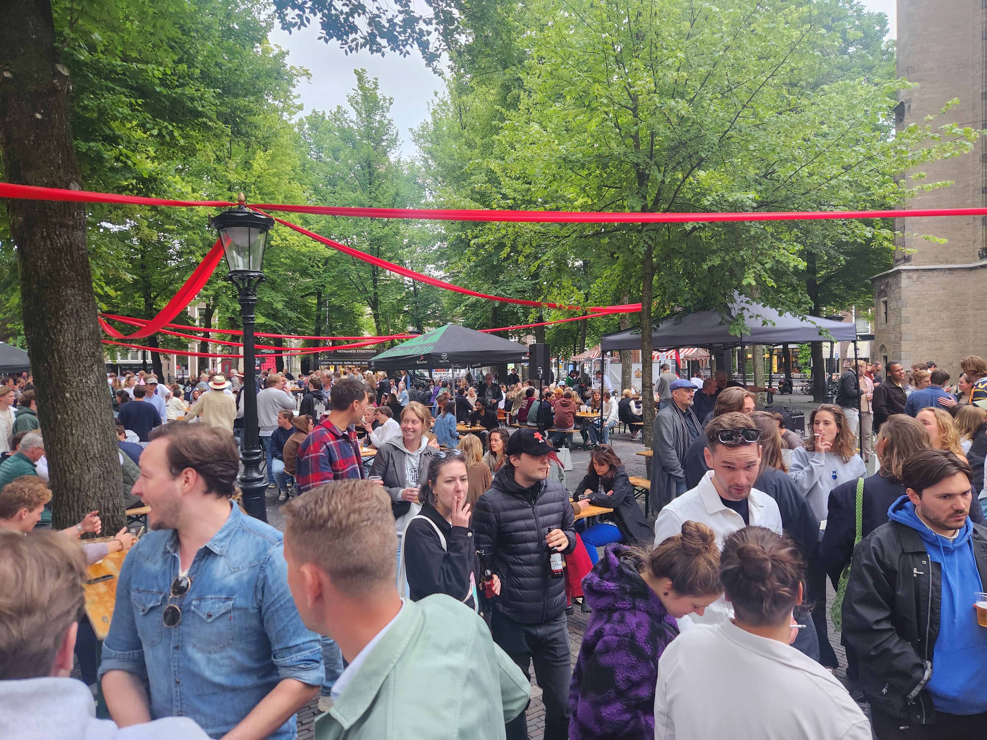 A large crowd at the Utrecht jazz festival, there red ribbons threaded across the lamp posts