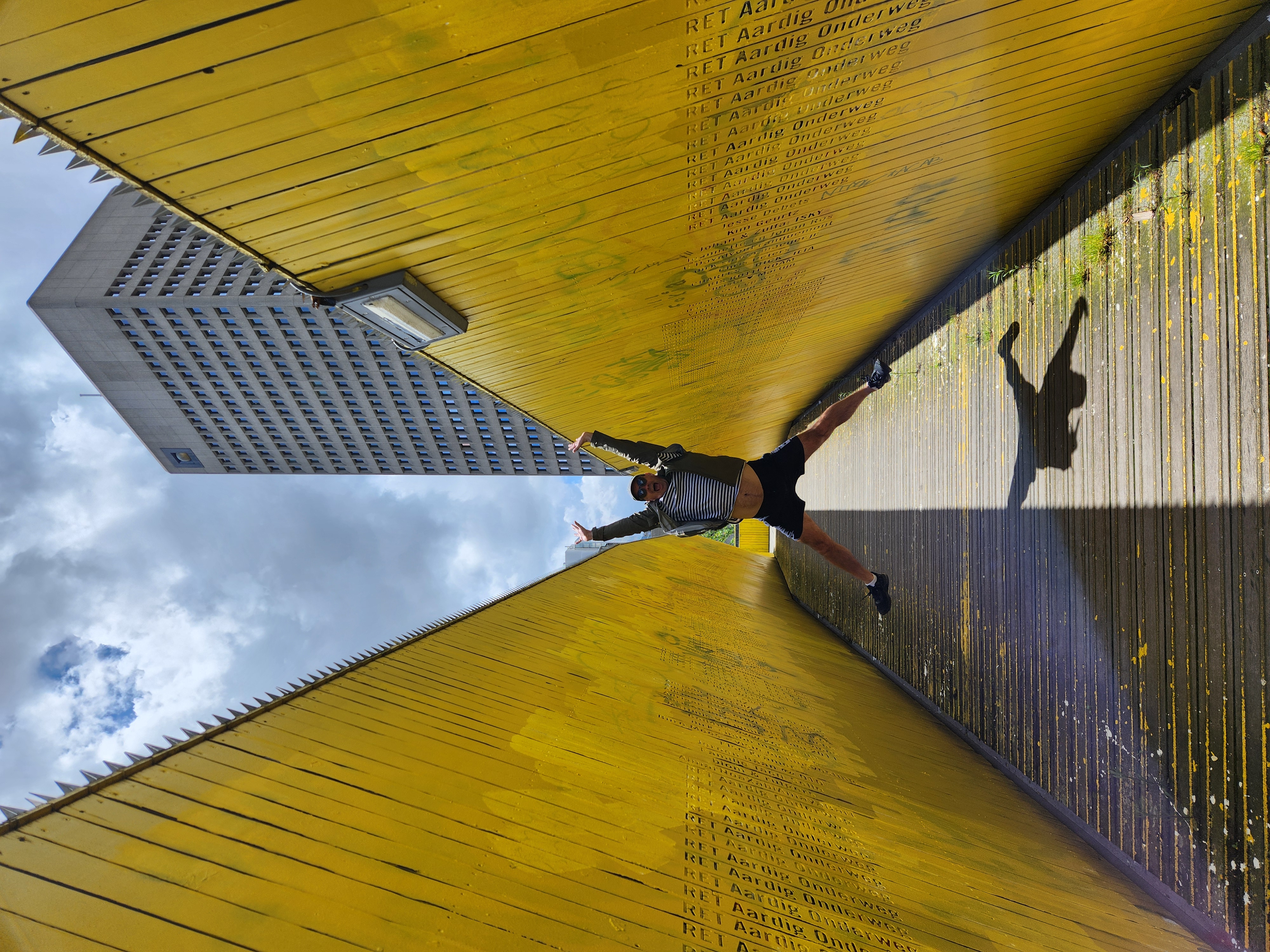 Mark doing a star jump inside the wooden luchtsingel pedestrian bridge, it is painted yellow